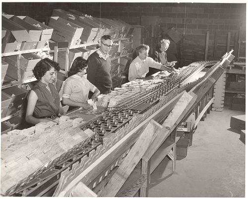 A black and white photo of people working in a factory