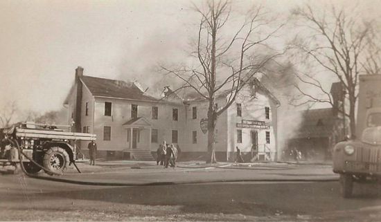 historic image of white building on fire with fire truck in front