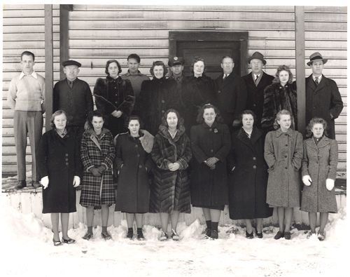 A group of people standing in front of a wooden building