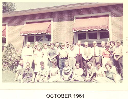 A group of people are posing for a picture in front of a building in october 1961.