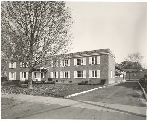 A black and white photo of a large brick building with white shutters