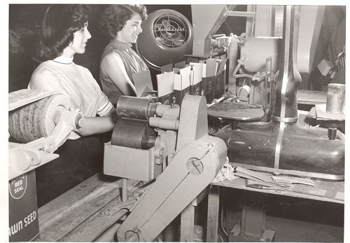 Two women are working on a machine in a black and white photo