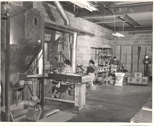 A black and white photo of people working in a factory