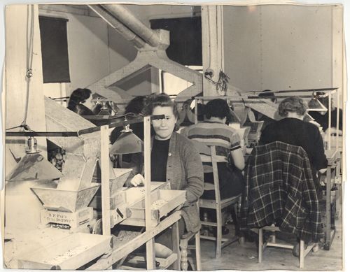 A black and white photo of people working in a factory