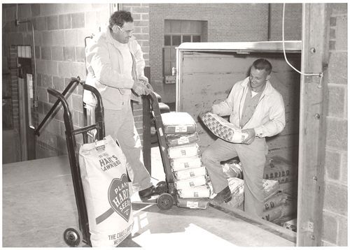 A black and white photo of two men pushing a cart