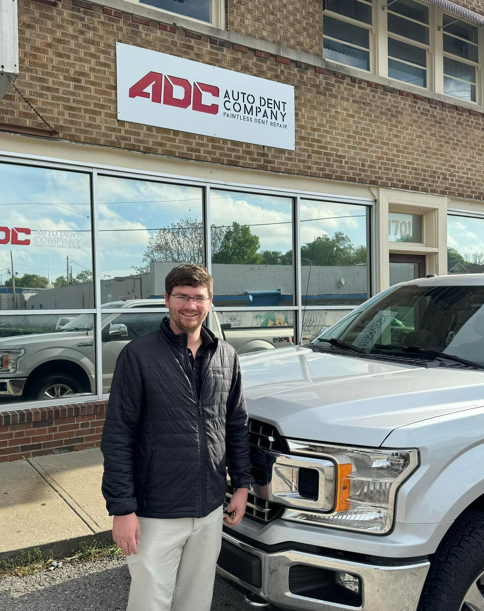 A man is standing in front of a truck in front of a building.