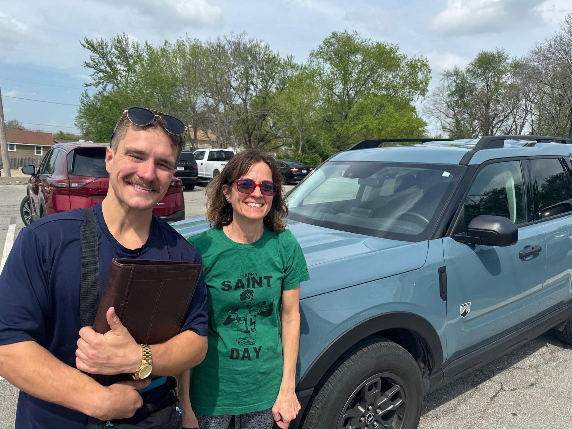 A man and a woman are standing next to a car in a parking lot.