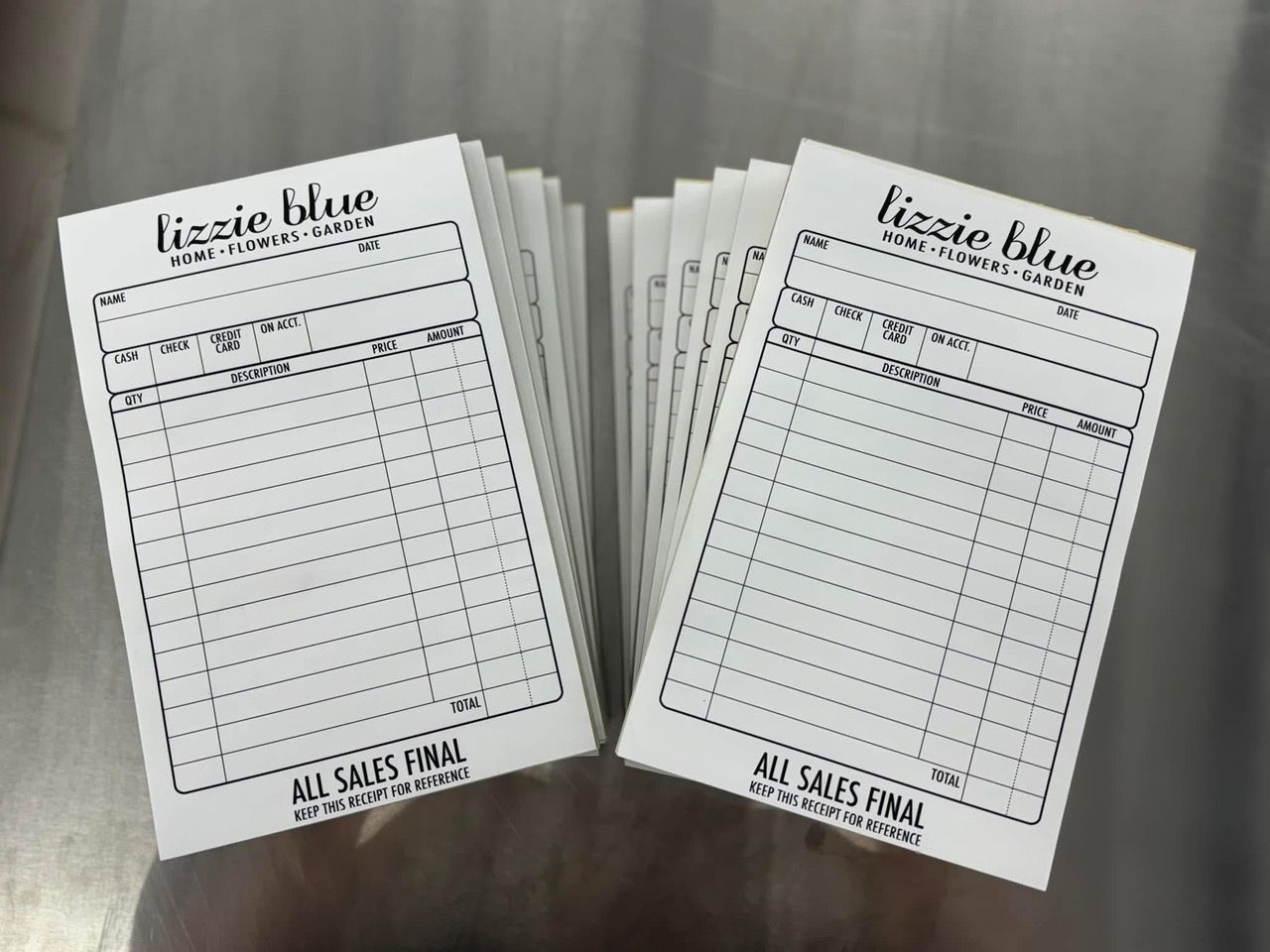 Stacks of white sales receipt pads with black text, 'Lizzie Blue' logo and 'ALL SALES FINAL' at the bottom.