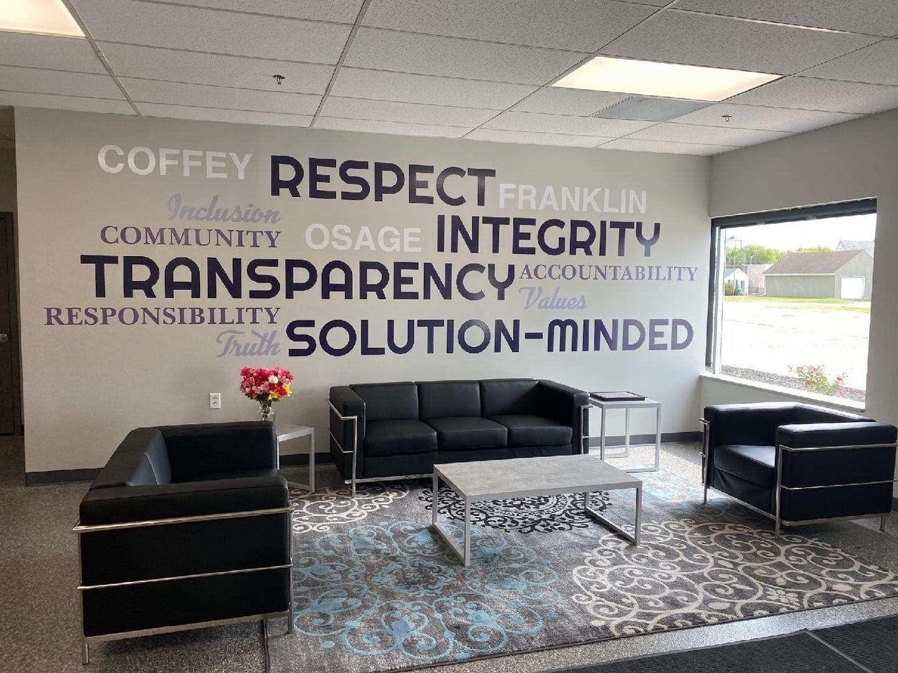 Reception area with black furniture, a patterned rug, and a wall with corporate values.