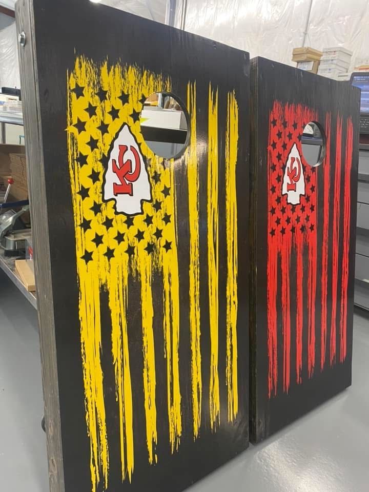 Two cornhole boards with a distressed flag design in yellow and red, with a team logo.