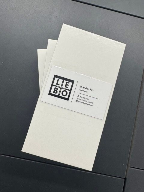White rectangular cards with a business card on top, LEBO logo, black table.