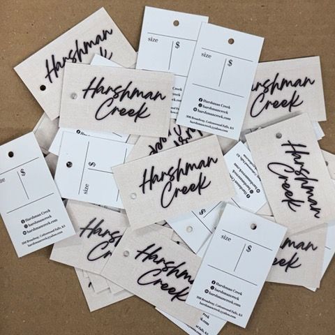 Pile of beige and white product tags with Harshman Creek and pricing details.