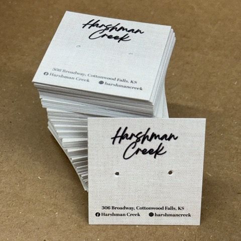 Stack of Harshman Creek earring display cards with two small holes. The cards have a business name, address, and social media handles.