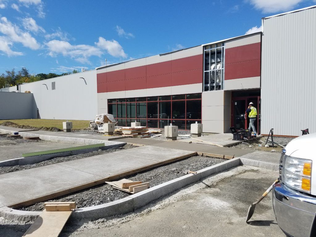 A white truck is parked in front of a building under construction.