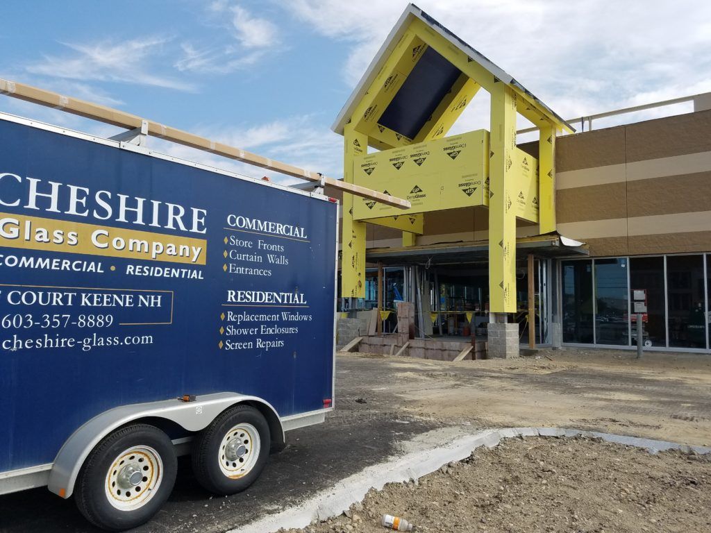 A cheshire glass company trailer is parked in front of a building