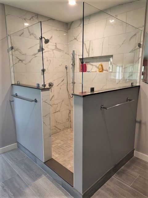 A bathroom with a walk in shower with a glass door