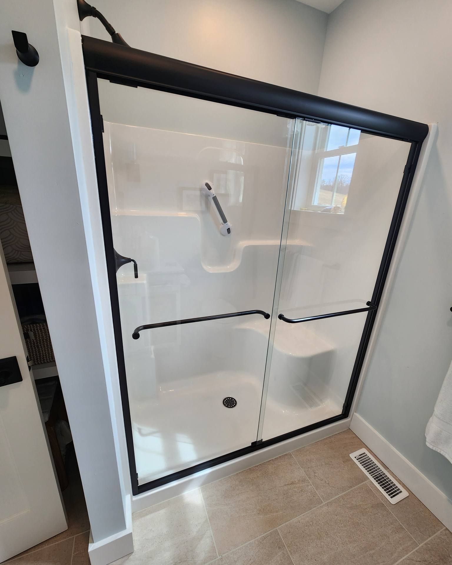 A bathroom with a walk in shower with a black frame.