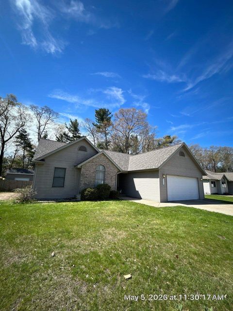 Suburban house with two-car garage under a bright blue sky, front lawn in spring.