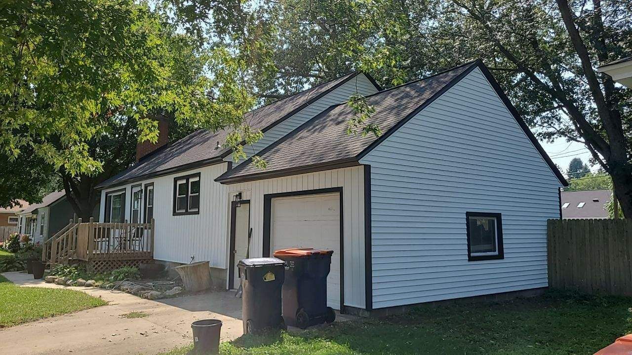 White house with blue siding, black trim, and a garage; trash cans in front.