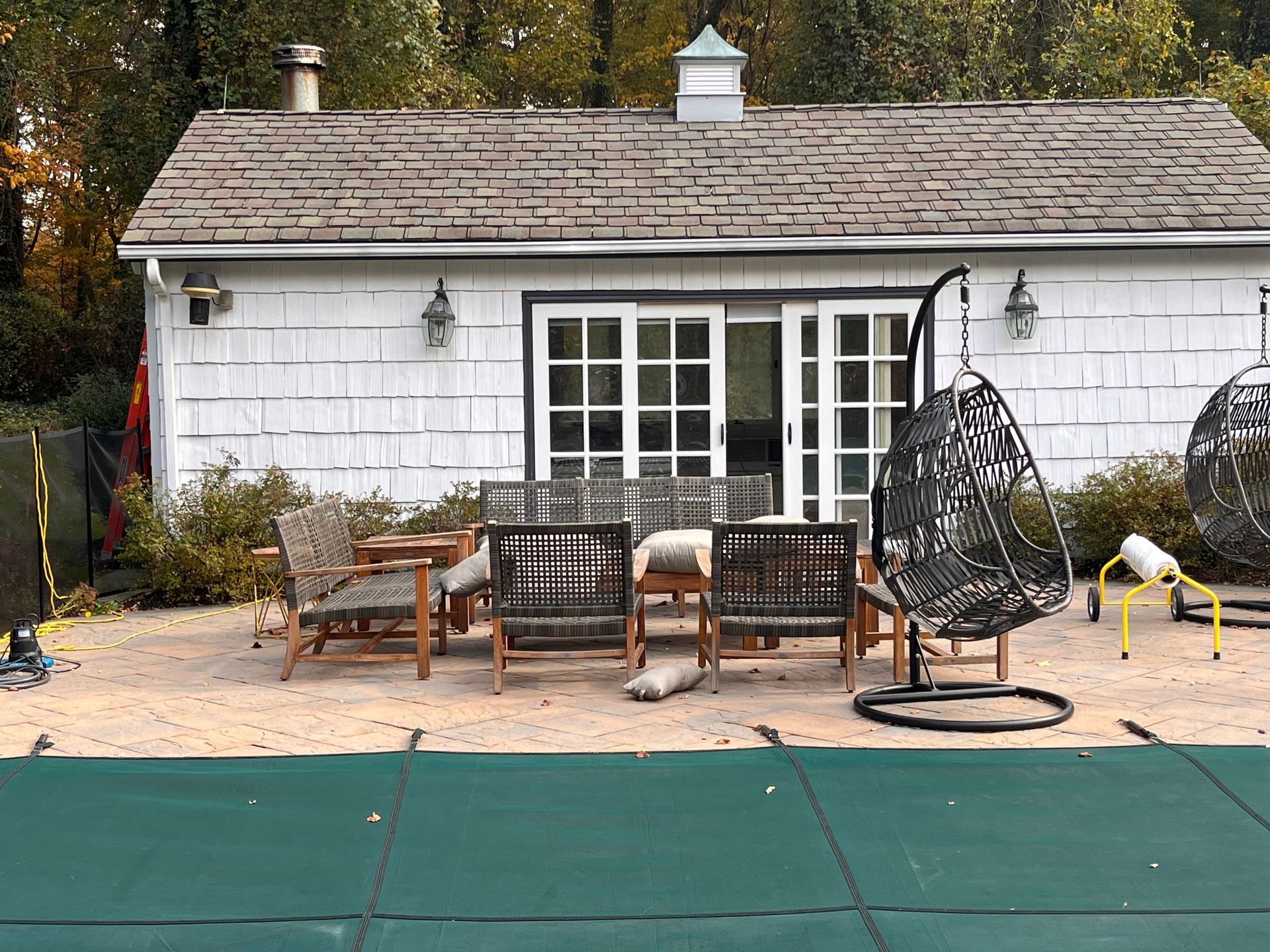 A white house with a pool and patio furniture in front of it