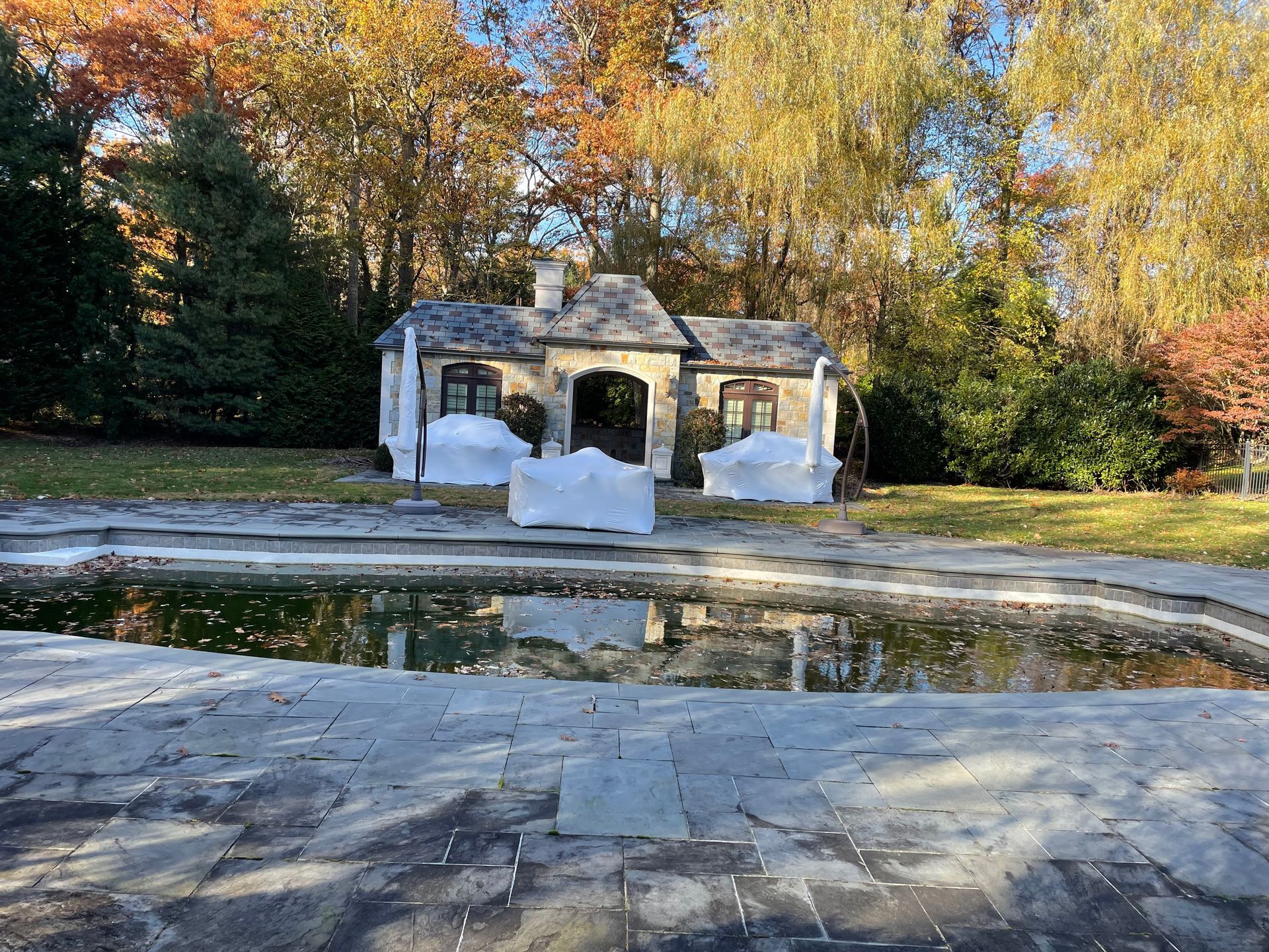 A small house is sitting next to a large swimming pool