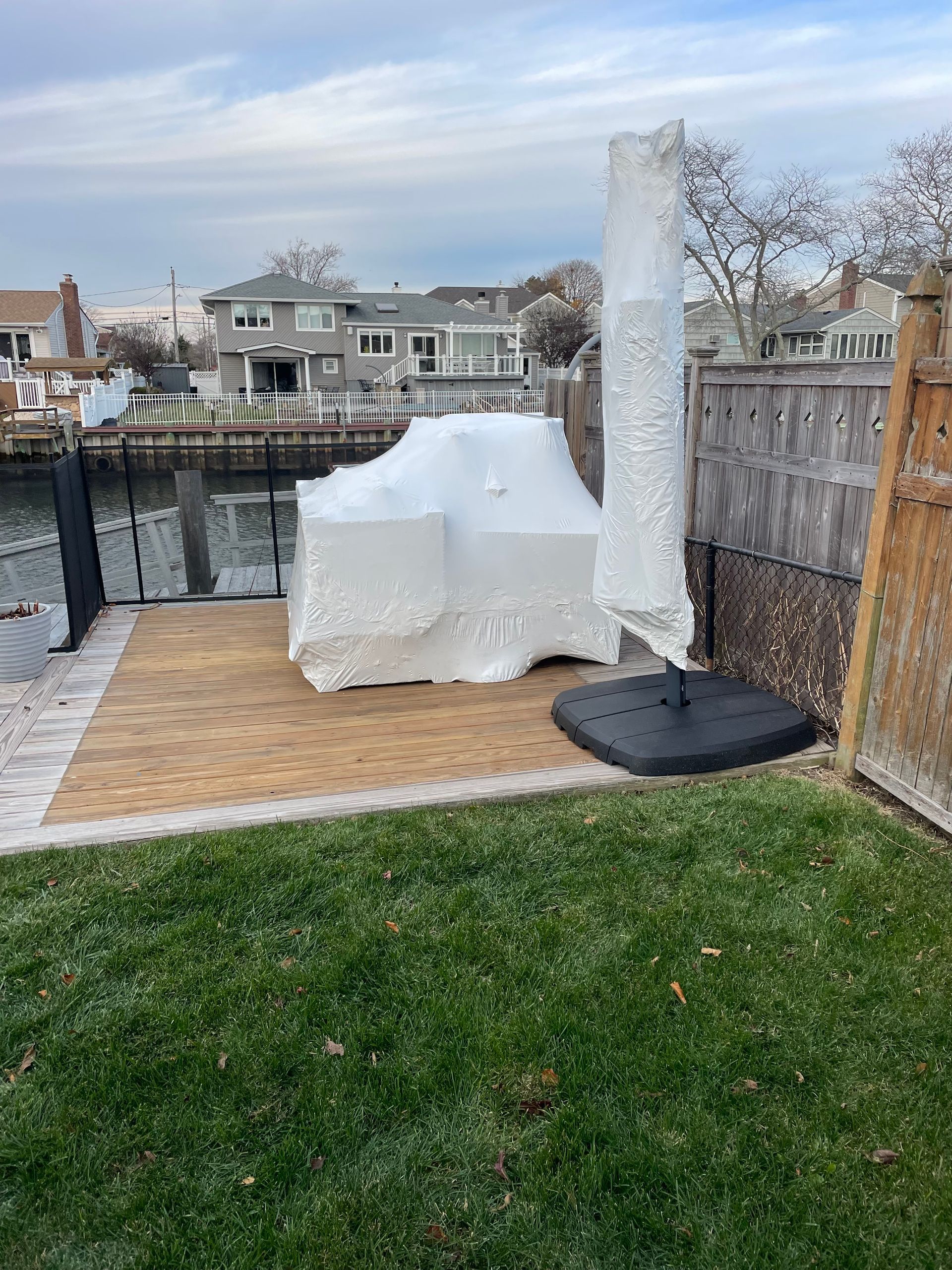 A white umbrella is sitting on top of a patio next to a body of water