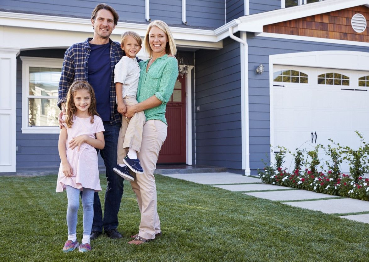 A family is standing in front of their new home.