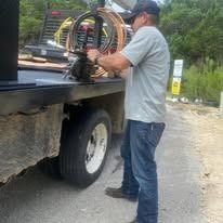 Man working on equipment on a truck bed, outdoors.