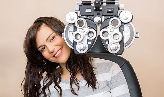 Young woman sitting behind optometer during an eye exam