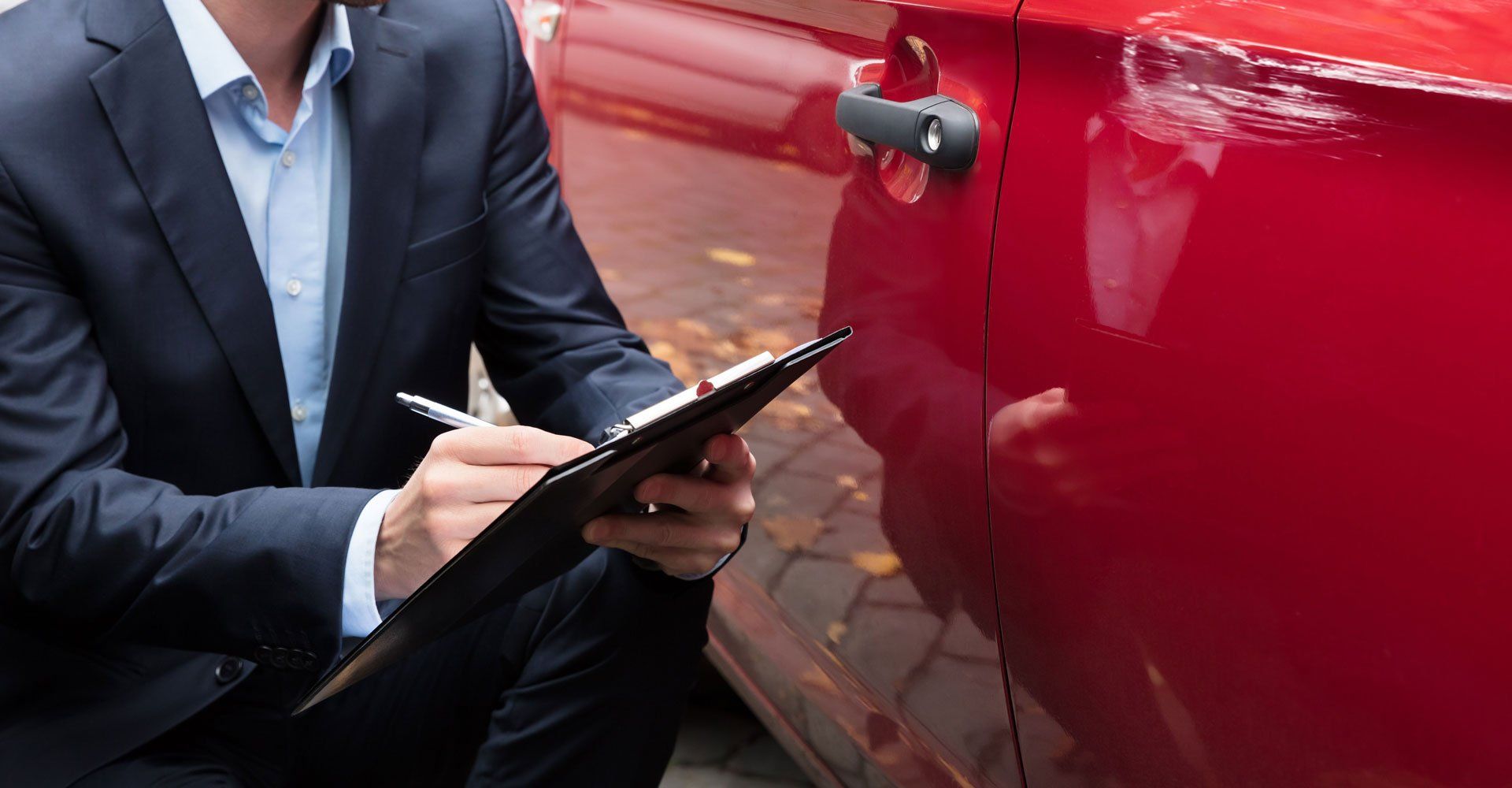 Insurance Agent Writing On Clipboard While Examining Car After Accident