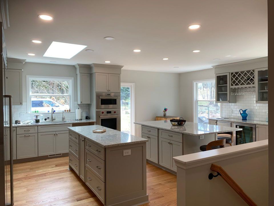 Bright modern kitchen with gray cabinets, white countertops, island, and large windows