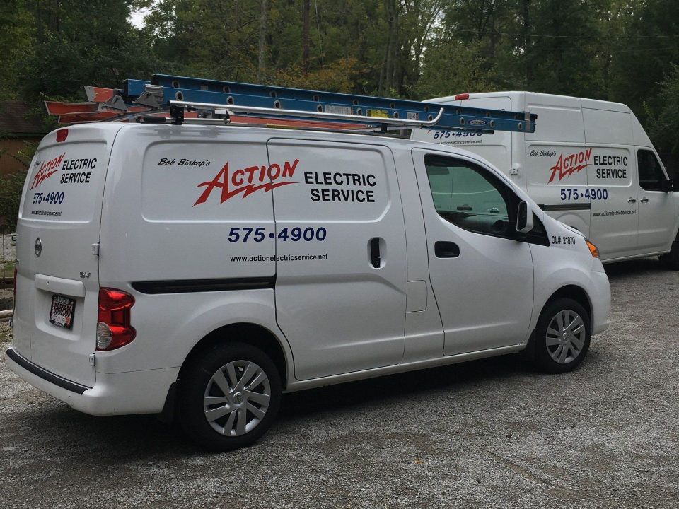 White Action Electric Service van with ladders parked beside a second service van outdoors.