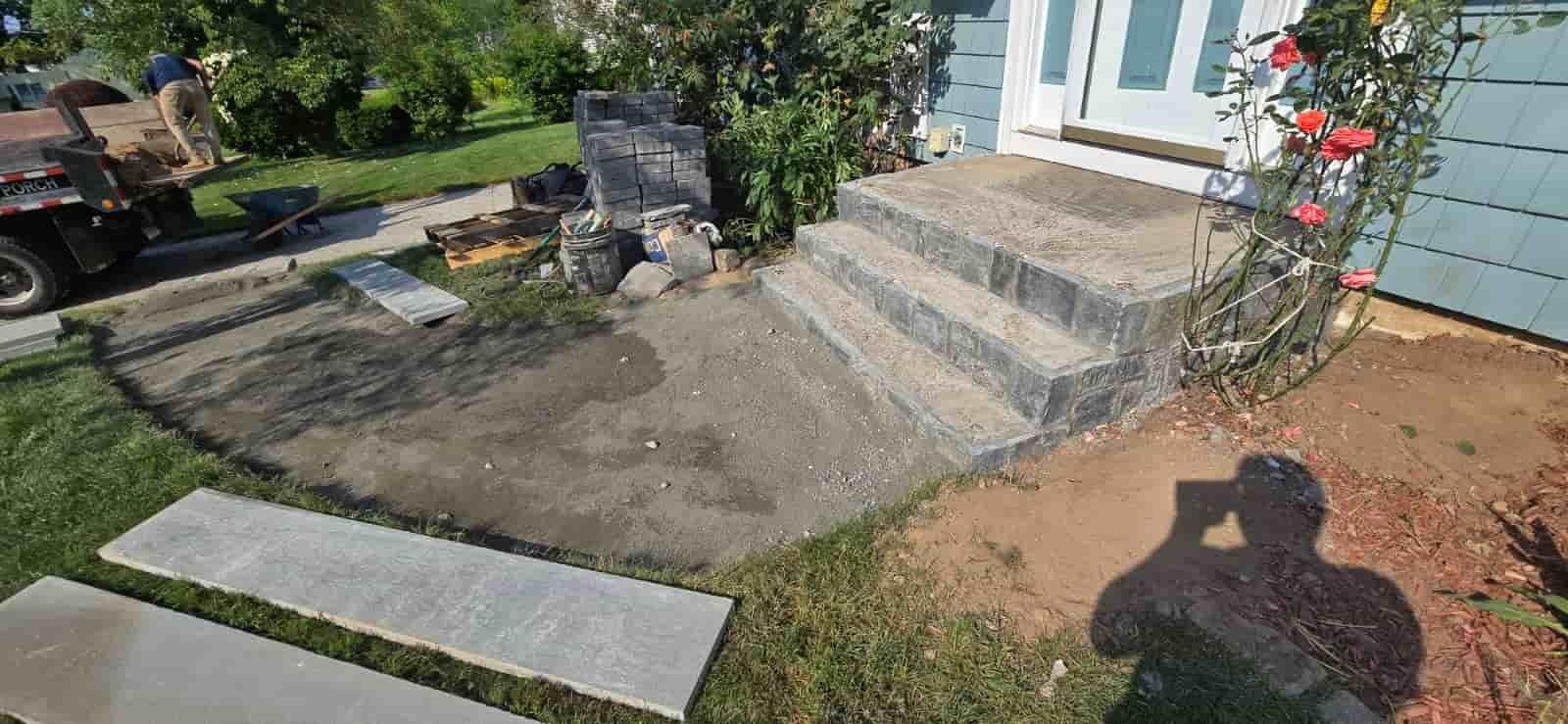 Front yard with concrete steps, garden beds, and a walkway beside a light blue house