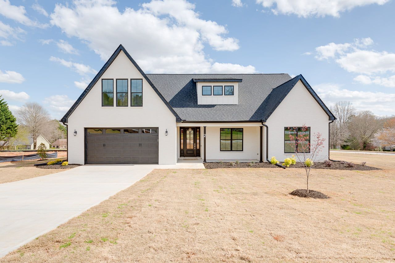 A white house with a black roof and a black garage door.