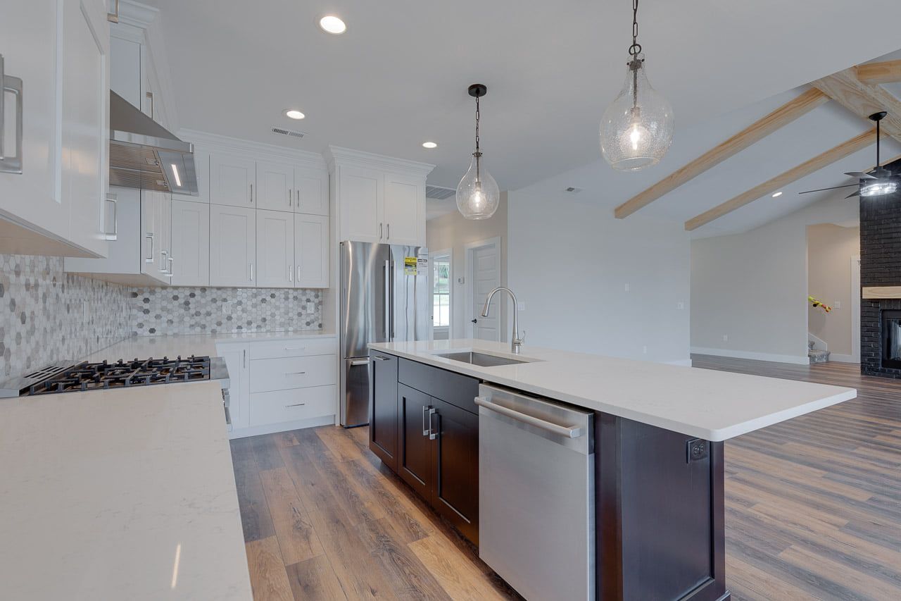 A kitchen with white cabinets , stainless steel appliances , and a large island.