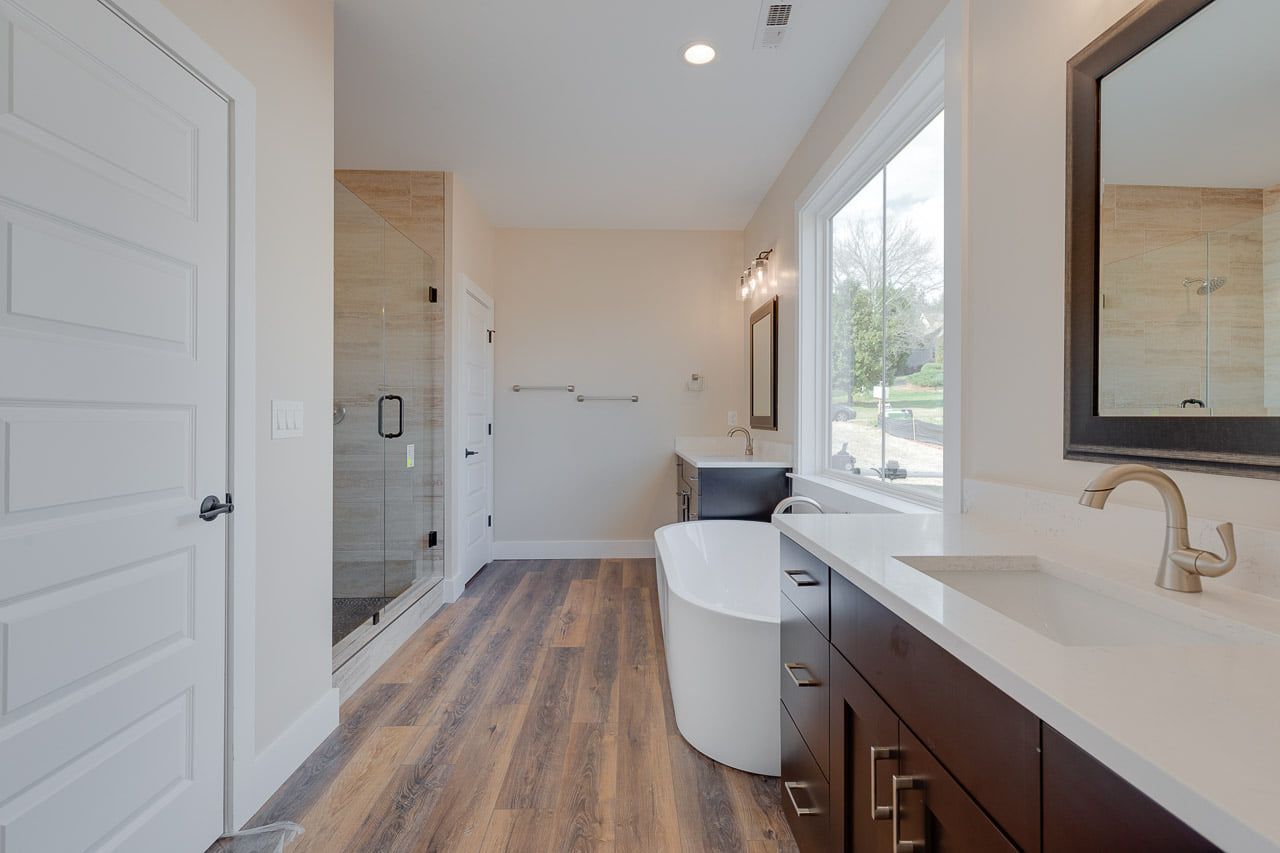 A bathroom with a tub , sink and mirror.