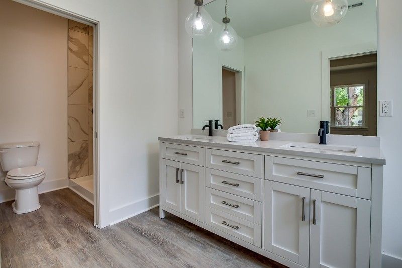 A bathroom with two sinks , a toilet , and a large mirror.
