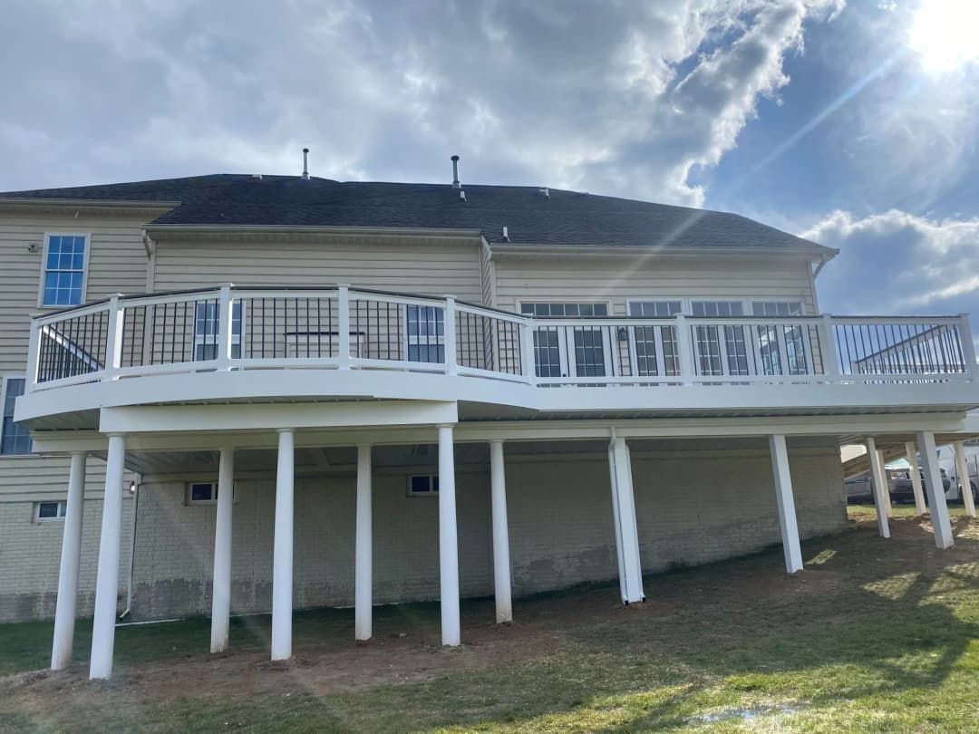 A two-story house with a white deck supported by pillars. Overcast sky.