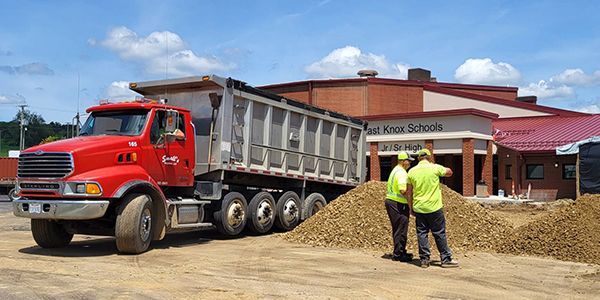 A red dump truck is parked in front of a building.