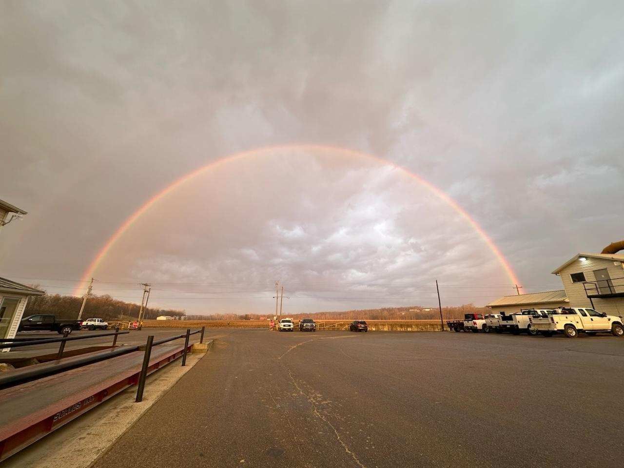 There is a rainbow in the sky over a parking lot.
