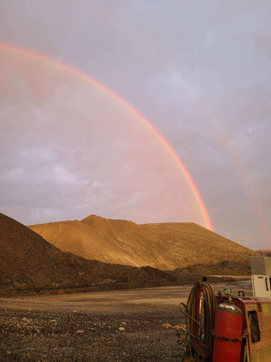 A rainbow is visible over a desert landscape with mountains in the background.