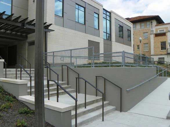 Accessible building entrance with stairs, railings, and a ramp beside a modern gray exterior