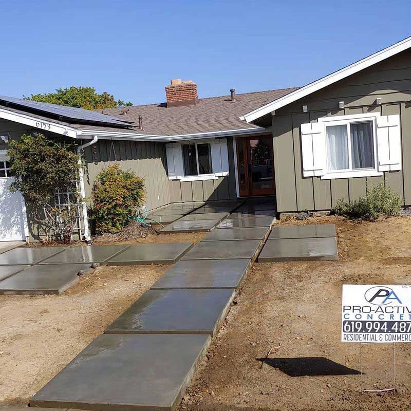 Front view of a house with a newly poured concrete walkway leading to the front door