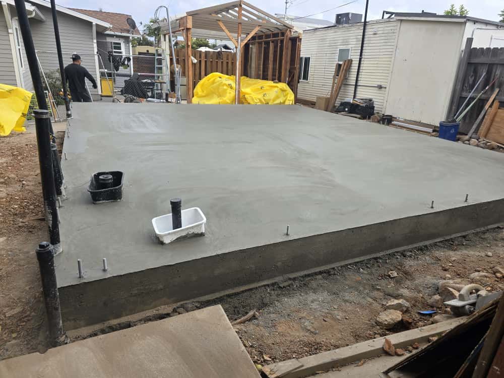 Concrete slab foundation under construction with tools and materials in a backyard site