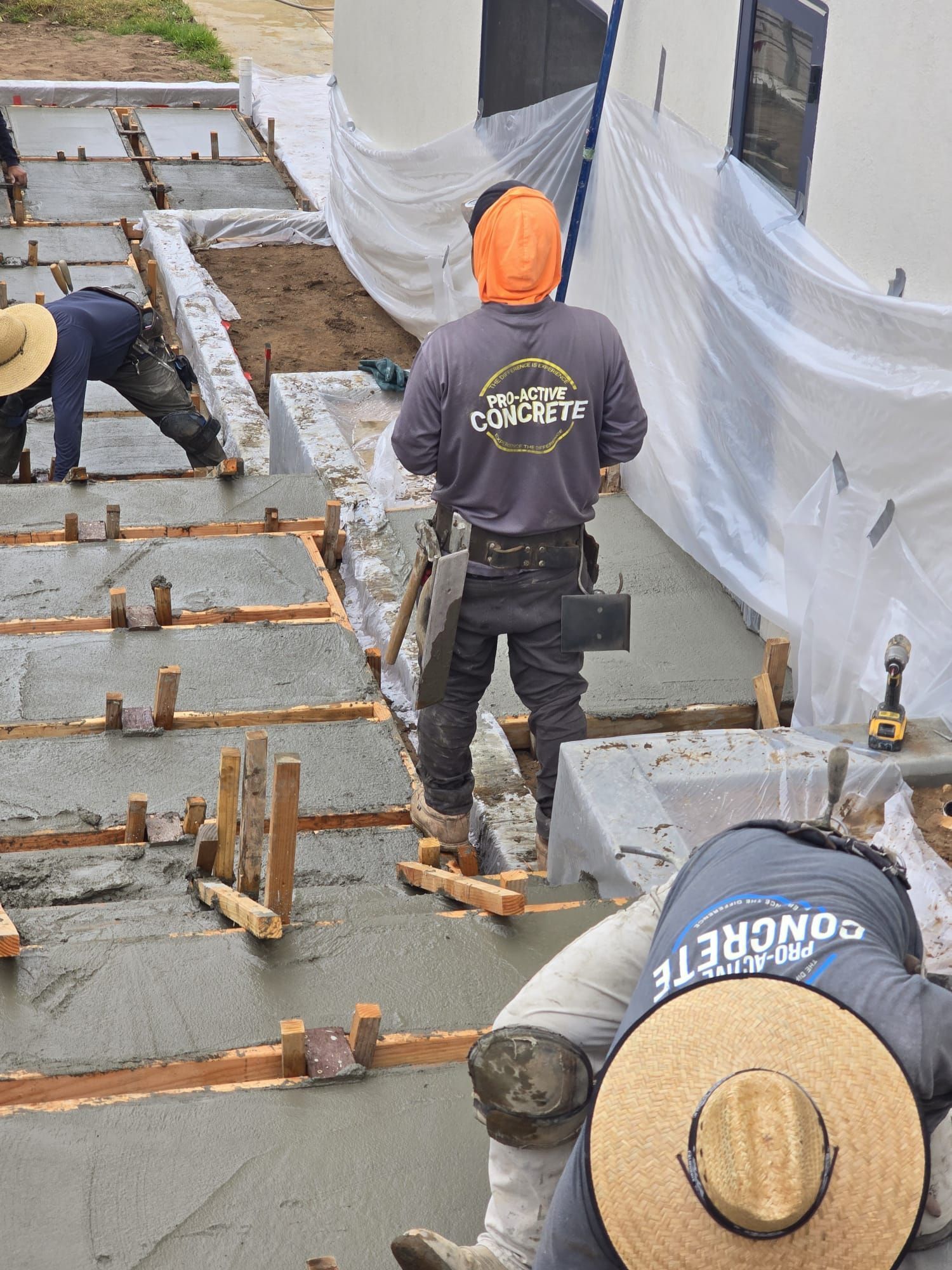 Construction workers laying rebar and forms on a concrete slab at a building site
