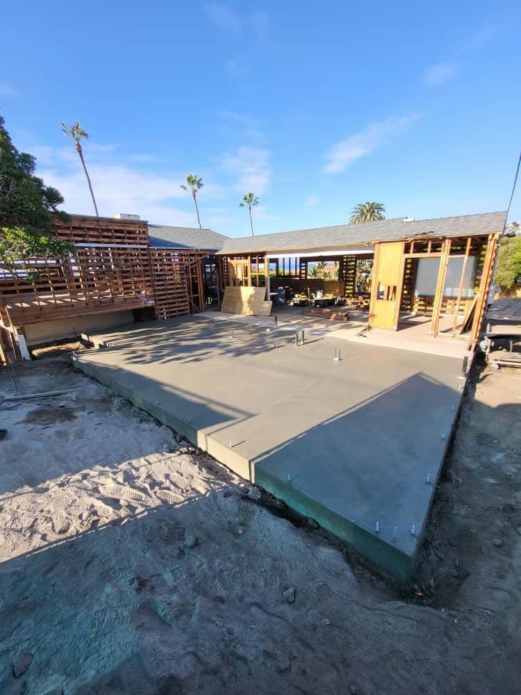 Partially built concrete patio with wooden framing in a sunny outdoor yard