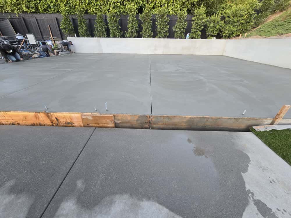 Freshly poured concrete driveway with wooden formwork and wet patch in the foreground.
