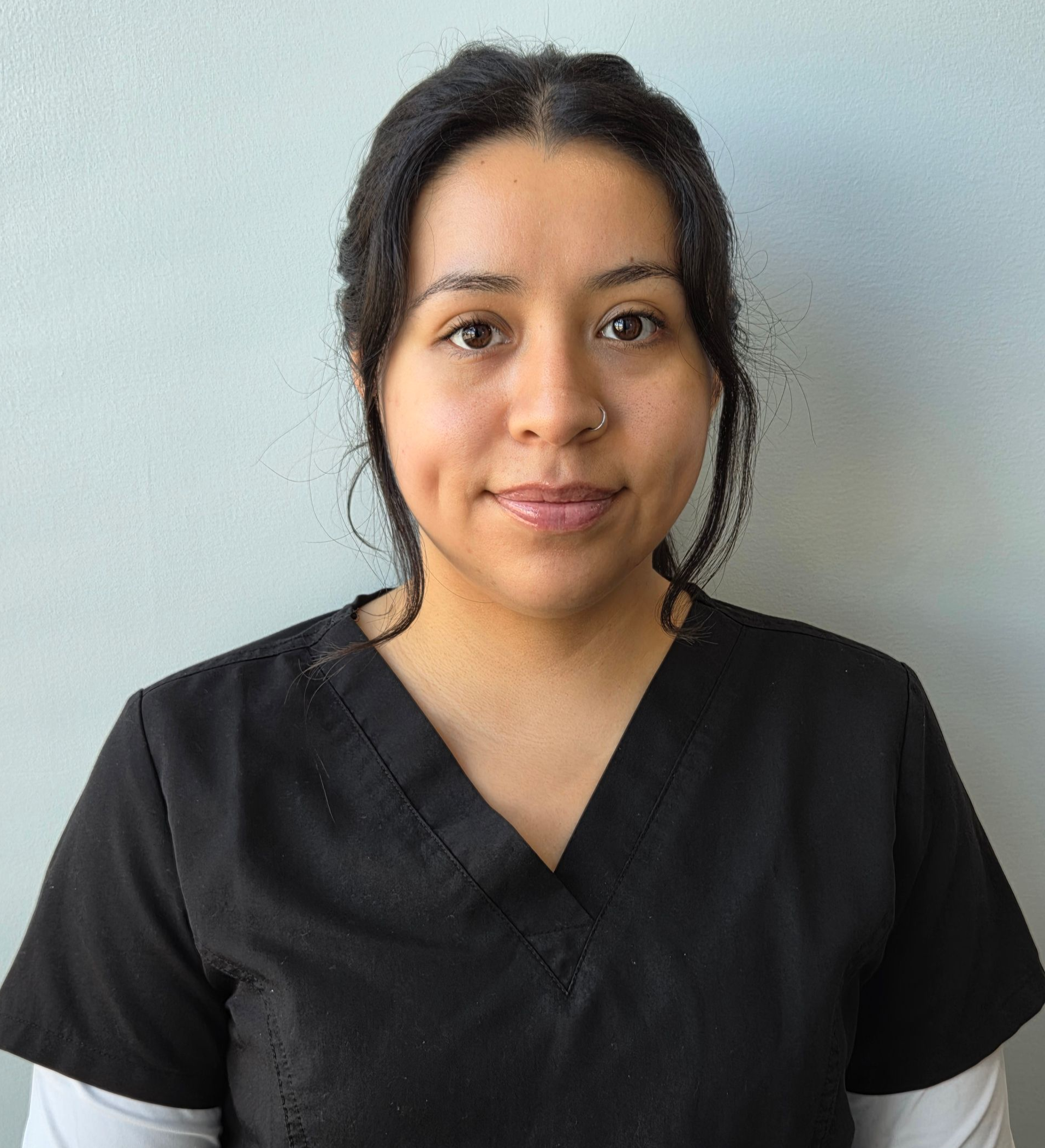 A woman in a blue scrub top is smiling for the camera