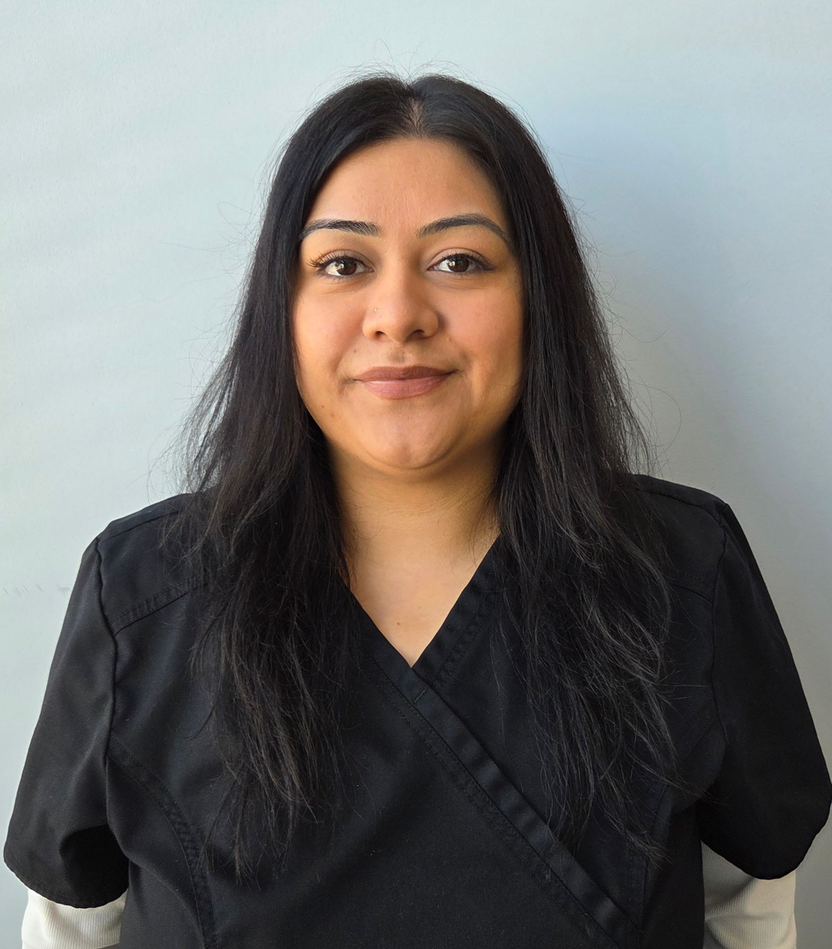 A woman wearing a blue scrub top that says ati dental care