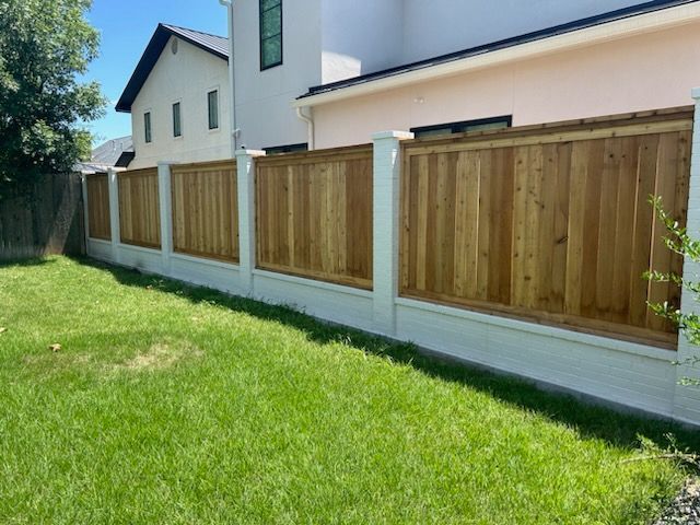 Wooden privacy fence along a grassy backyard beside a house
